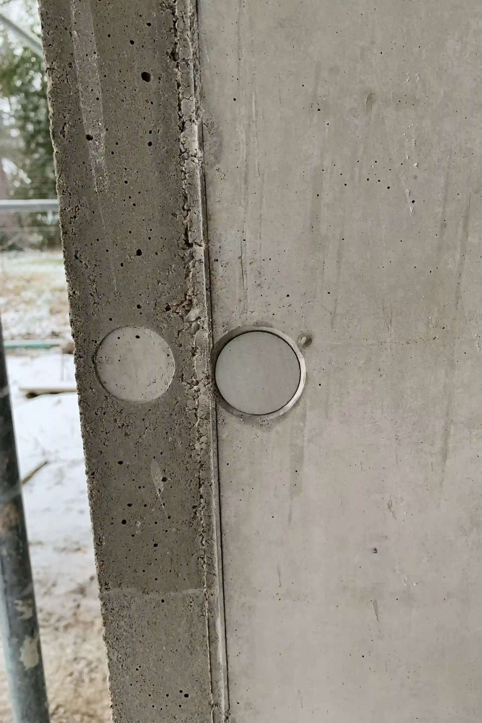 Sichtbetonwand mit eingesetzten Ankerkonen – sauber verschlossene und angepasste Oberfläche.